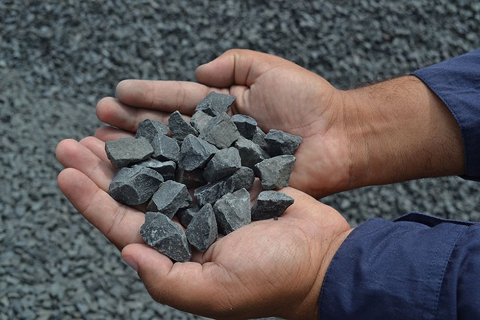 Hands holding grey aggregate.