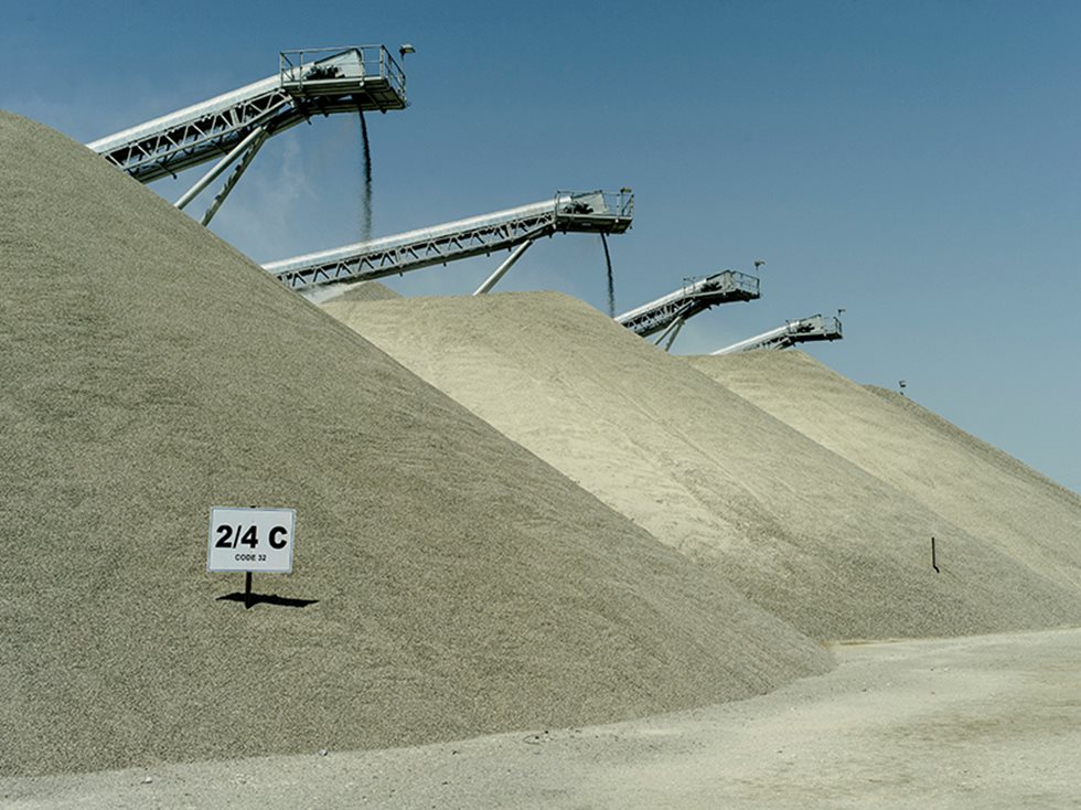 Three piles of processed aggregates with parts of conveyors peaking on top.